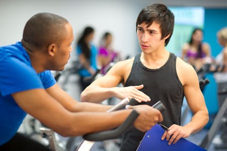 Physical therapist holding a blue clipboard while explaining a workout to a patient