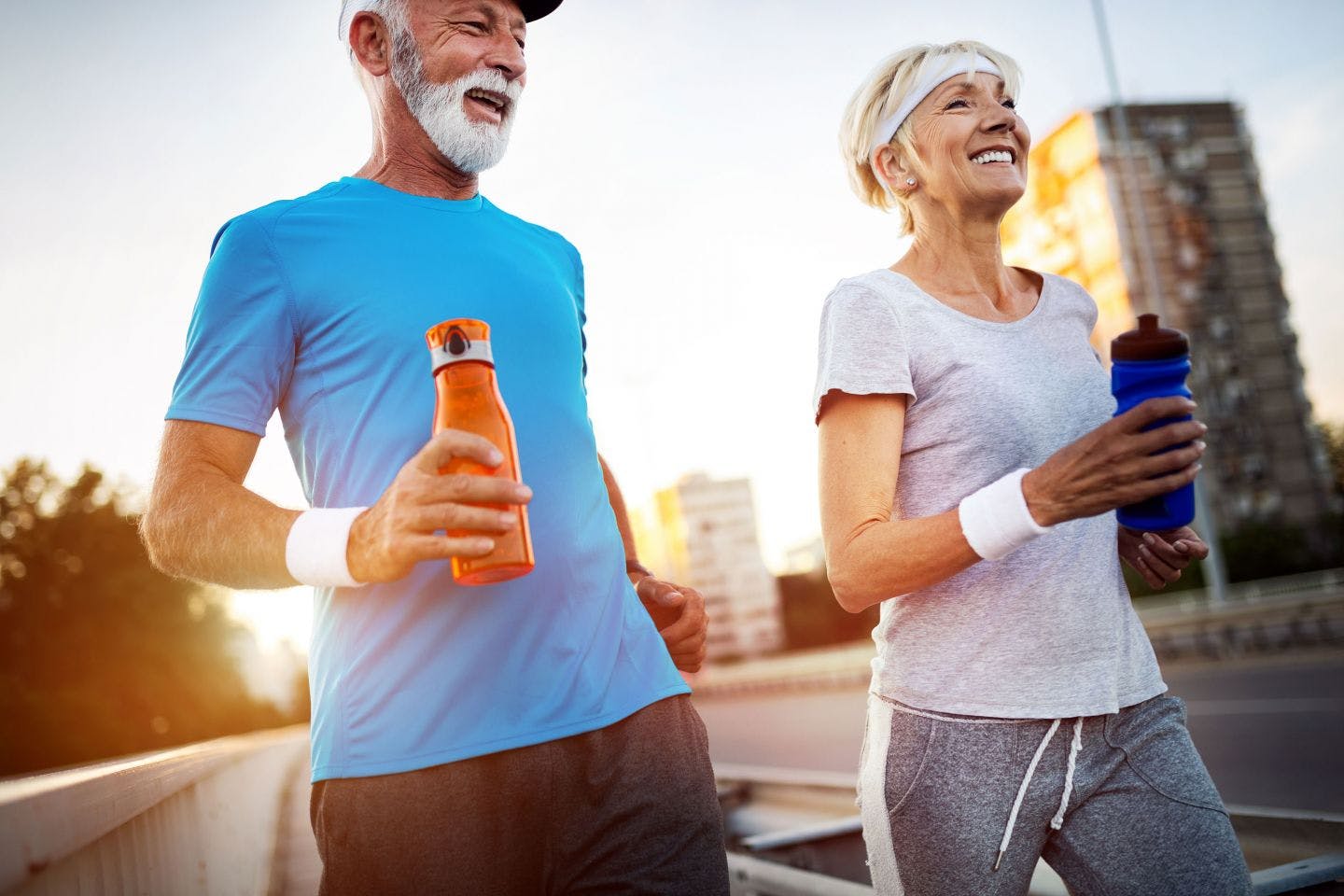 A man and woman running together while holding bottles of water